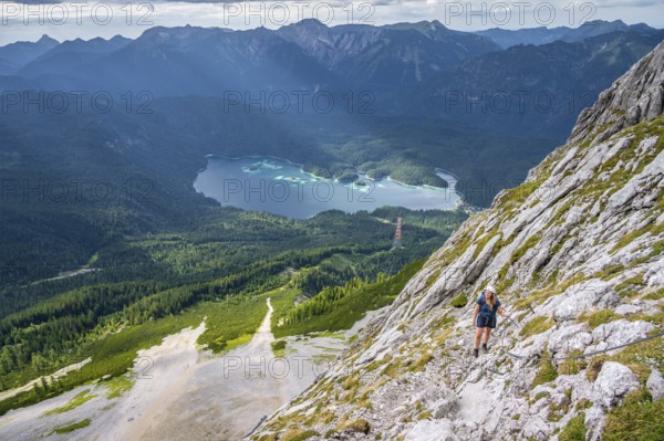 Via ferrata over the Riffelscharte, hiker in the mountains, view of Eibsee lake and Werdenfelser