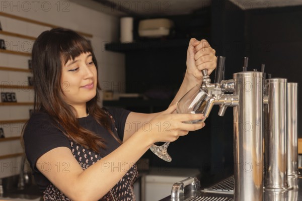 Young waitress with her hair pulled back serving beer at the bar in a restaurant