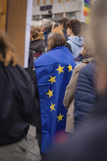 Person wearing an EU flag as a cloak at a public gathering, Against the Right Demo, Nagold, Black