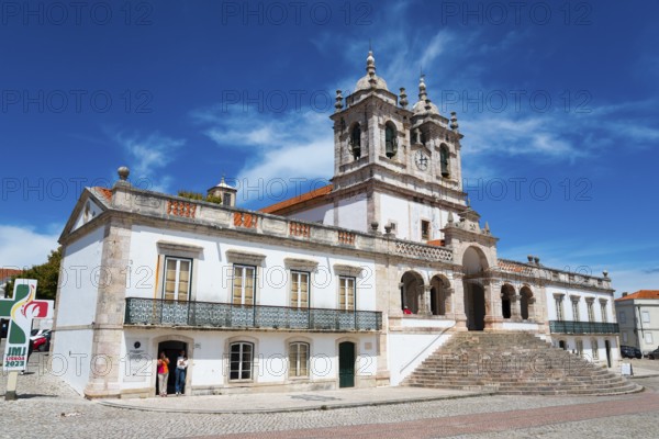 Baroque church building with striking towers, wide stone steps and bright facades under a blue sky,