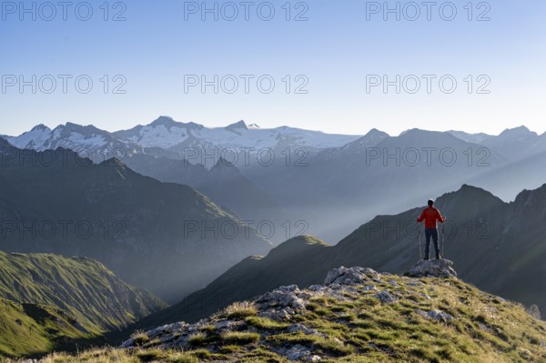 Mountaineer with poles on the summit of the Bachlenkenkopf at sunrise, atmospheric mountain