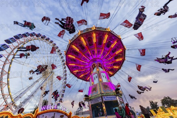 Chain carousel and Ferris wheel in the evening. 177th Cannstatter Volksfest at the Cannstatter