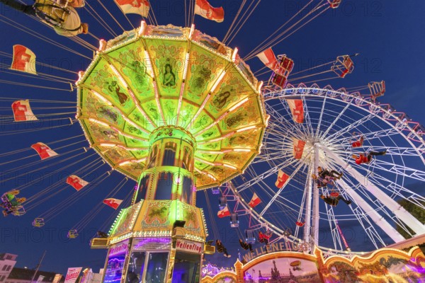 Illuminated carousel and Ferris wheel at night in a lively amusement park, funfair, wave flight,