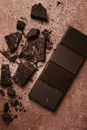Chocolate bar, for the manufacture of confectionery, broken, crumbled, on a brown background, top