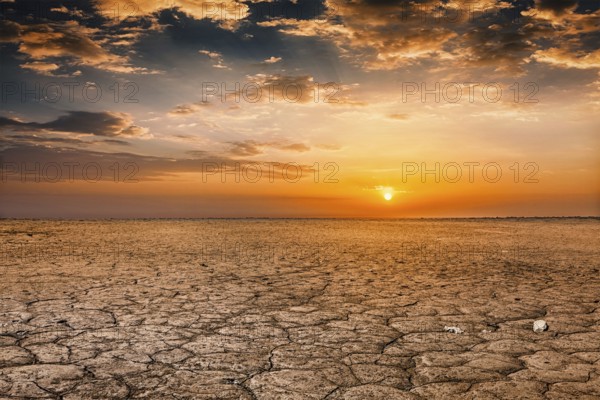 Global worming concept, cracked scorched earth soil drought desert landscape dramatic sunset
