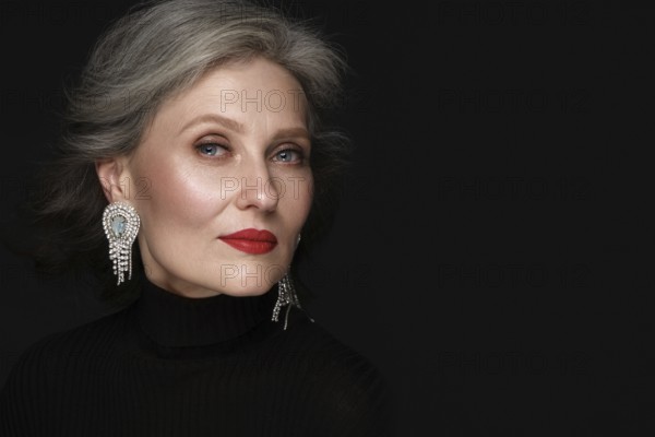 Portrait of a beautiful elderly woman in a white shirt with classic makeup and gray hair