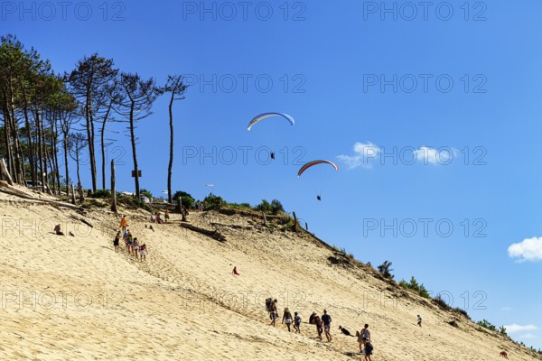 Two paragliders approaching, walkers, tourists on dune, Dune du Pilat, view from below, Arcachon,