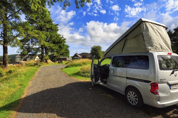 Campervan with pop-up roof, opened roof, mini camper Nissan NV200, camping on a farm, sunny