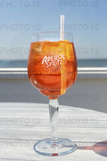 Glass of Aperol Spritz in front of the sea, horizon