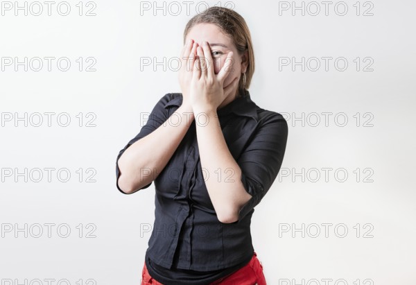Embarrassed girl covering her face and looking at the camera. Shy girl covering her face and