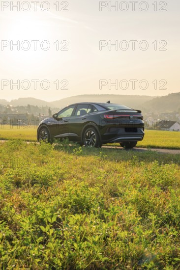 SUV on a rural road with a view of the hills in the background, at sunset, VW ID5 electric car,