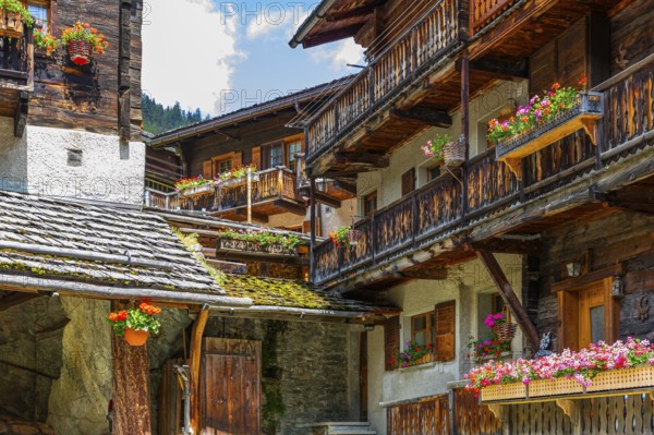 Nested old wooden houses with flower boxes in front of windows and balconies, historic village