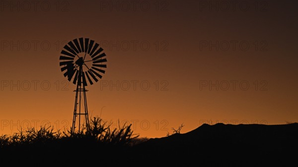 A wind-powered water pump at sunrise, Namibia, Africa