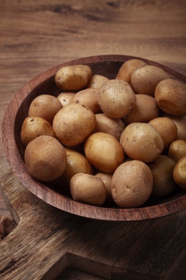 Small, unpeeled potatoes gathered together in a rustic wooden bowl, highlighting their earthy