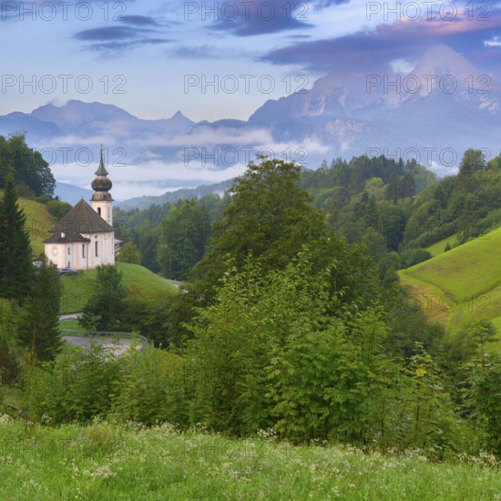 Maria Gern church in a picturesque mountain landscape, surrounded by dense green vegetation and