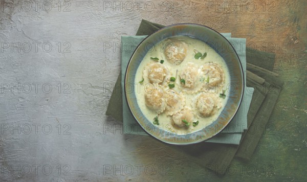 Ravioli in cream sauce, spices and herbs, top view, no people