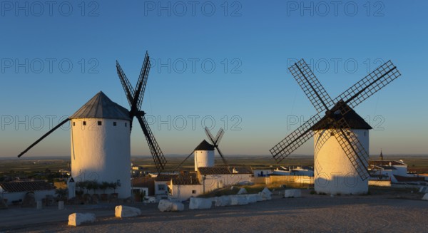 Three white windmills in a sunny landscape at sunrise in Spain, Campo de Criptana, province of