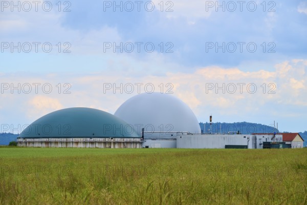 Modern biogas plant in the middle of green fields under a cloudy blue sky, summer, Middle