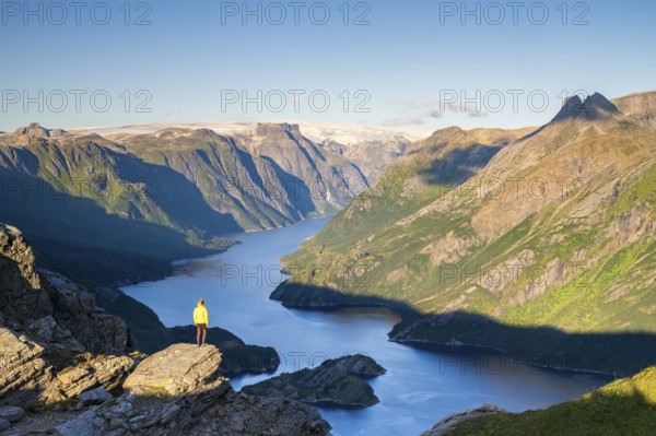 Hiker looking from Seiskallåfjellet into the Nordfjorden, Svartisen Glacier in the background,