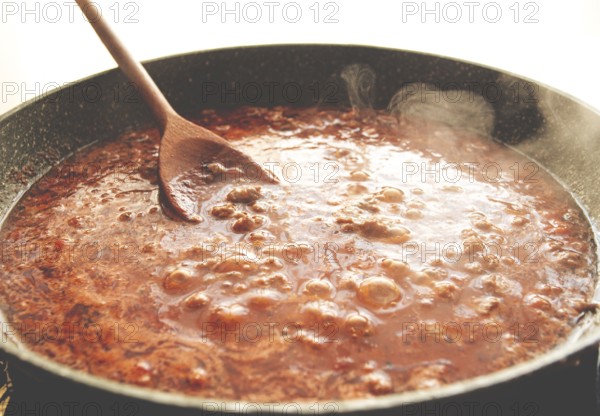 Cooking, bolognese sauce, in a frying pan, stirring with a wooden spoon, tomato meat sauce,