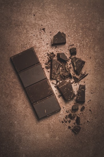 Chocolate bar, for the manufacture of confectionery, broken, crumbled, on a brown background, top