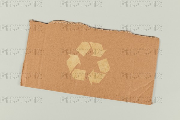 Red recycling arrow symbol on piece of cardboard
