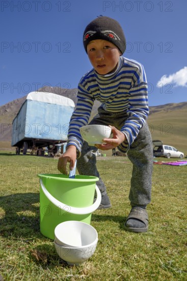 Shepherd boy scooping from a bucket of fermented mare's milk, West Karakol Valley, Tien Shan
