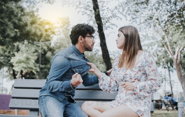 Upset couple arguing on a park bench. Young couple arguing sitting on a park bench, Concept of