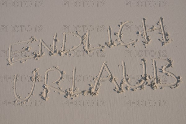 Writing in the sand "endlich Urlaub", German for "finally holidays"