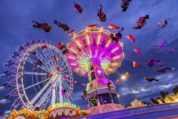 Chain carousel and Ferris wheel in the evening. 177th Cannstatter Volksfest at the Cannstatter