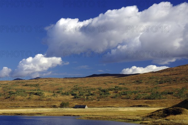 Gentle hills and wide grassland under a clear blue sky with white clouds, autumn, October,