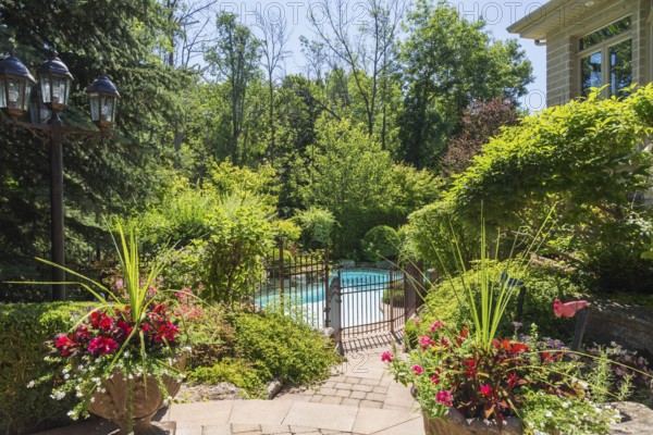 In-ground swimming pool surrounded by copper coloured wrought iron metal security fence and various