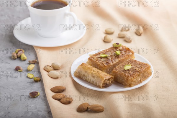 Traditional arabic sweets (basbus, kunafa, baklava) and a cup of coffee on a gray concrete