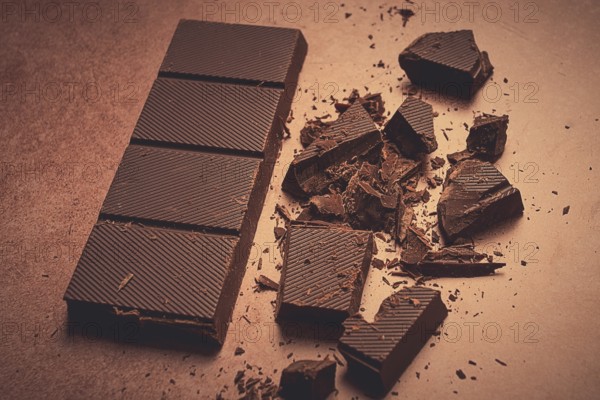 Chocolate bar, for the manufacture of confectionery, broken, crumbled, on a brown background, top