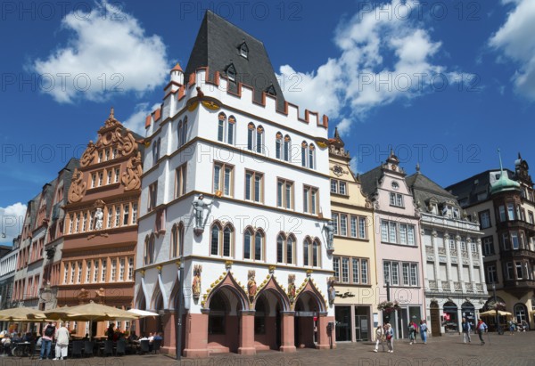 Historic old town with half-timbered houses, blue sky and cafés, animated by tourists under summer