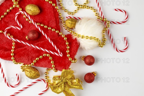 Christmas hat with candy canes, golden pearl necklace and nuts on a white background