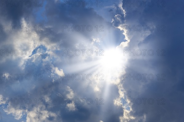 Rain clouds with sun shining through, rays of sunshine, blue sky