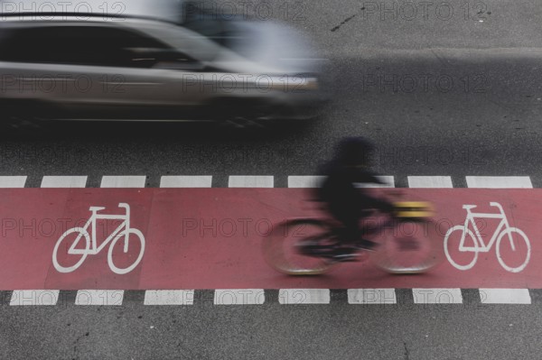 A cyclist rides on a marked cycle path on Schlossstraße and is overtaken by a car in Berlin,