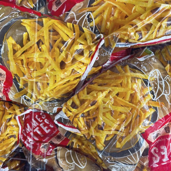 Display of deep-frozen French fries in freezer cabinet with transparent lid of supermarket,