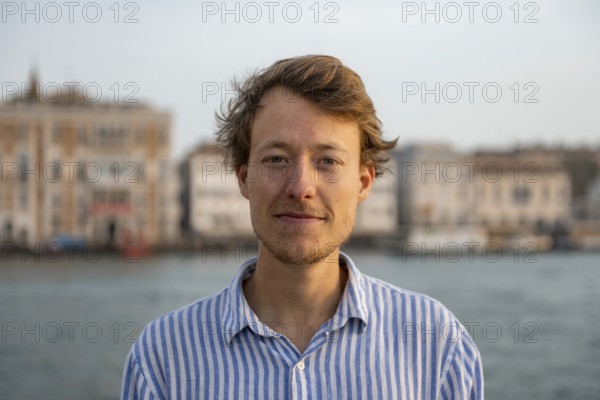 Young man in striped shirt, portrait, on the banks of the Grand Canal, looking into the camera,
