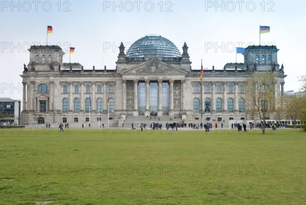 The Reichstag building in Berlin with visitors in front of it, German flags, European flag, flags,