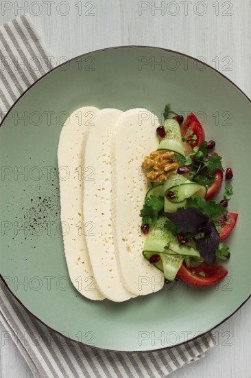 Sliced Imeruli cheese, Georgian cheese, with vegetables, top view, no people