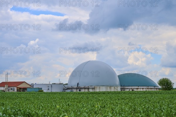 Modern biogas plant in the middle of green fields under a cloudy blue sky, summer, Middle