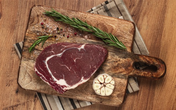 Raw steak, beef steak, rib eye steak, on a cutting board, freshly frozen, with spices and herbs, on