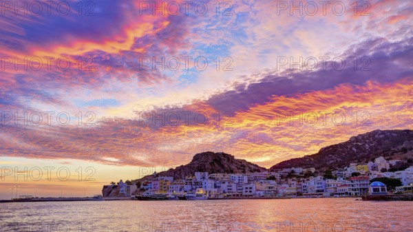 Atmospheric coastal panorama at sunrise with vivid colours in the sky and a small town by the sea,