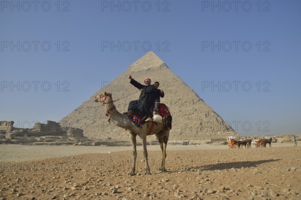 Camel owners on a camel in front of the Pyramid of Chephren, Giza, Egypt, Africa