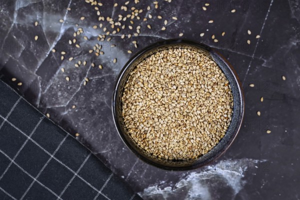 Top view of white sesame seeds in bowl on dark background