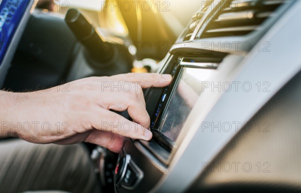 Close up of hands changing the car radio station. Concept of driver tuning the radio. Driver man