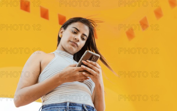 Portrait of attractive latin girl messaging on cell phone. Low angle of a beautiful Latin girl