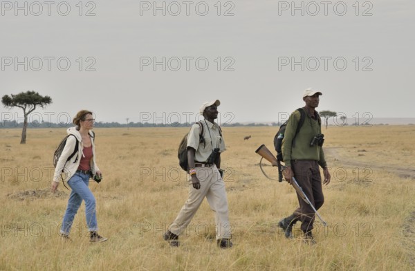 Tourist with armed guard and guide on a walking safari, Massai Mara, Serengeti, Rift Valley
